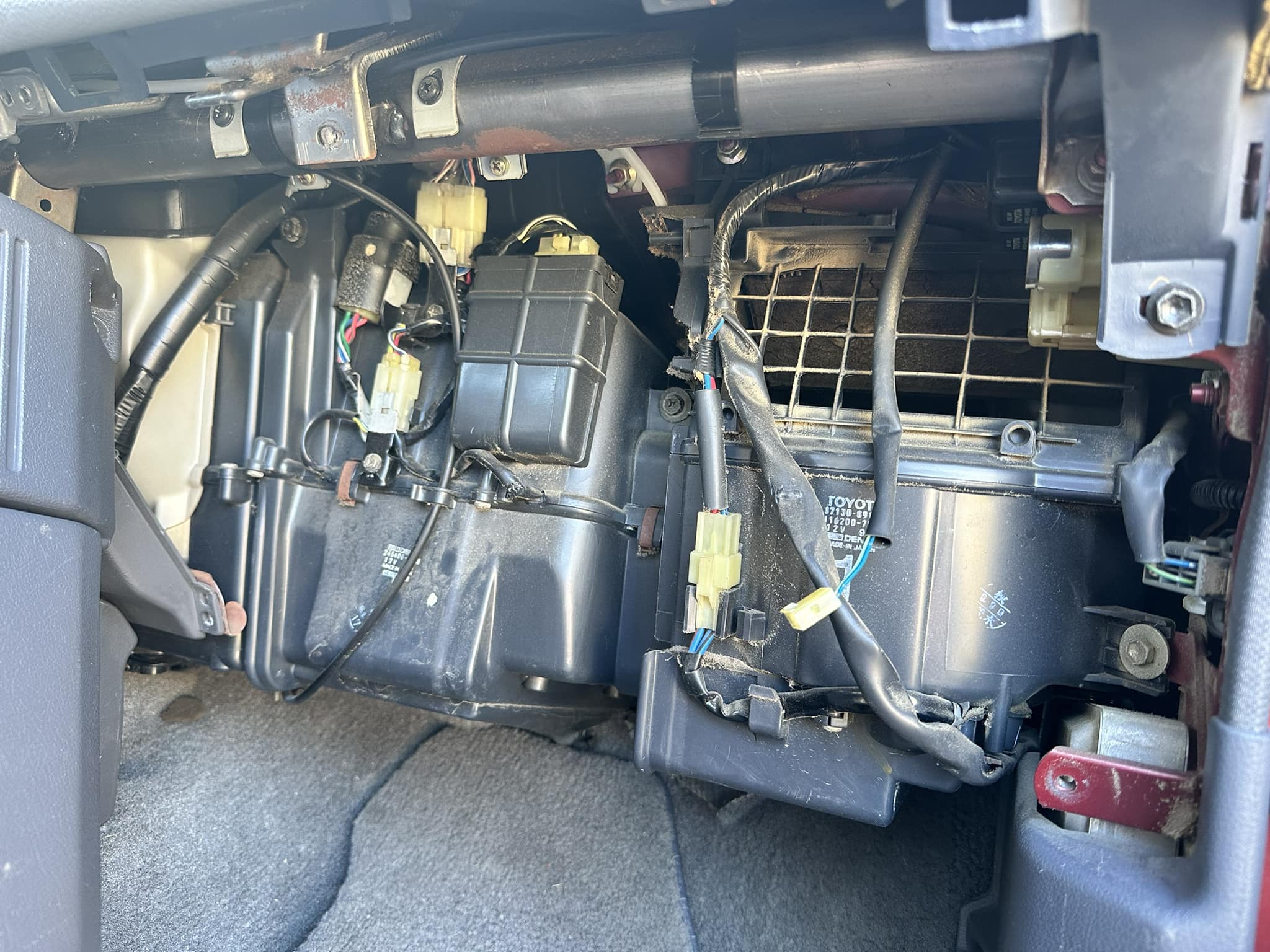 Primer plano del sistema de climatización de un auto visto desde detrás de la guantera, mostrando la ubicación de la resistencia del motor soplador.