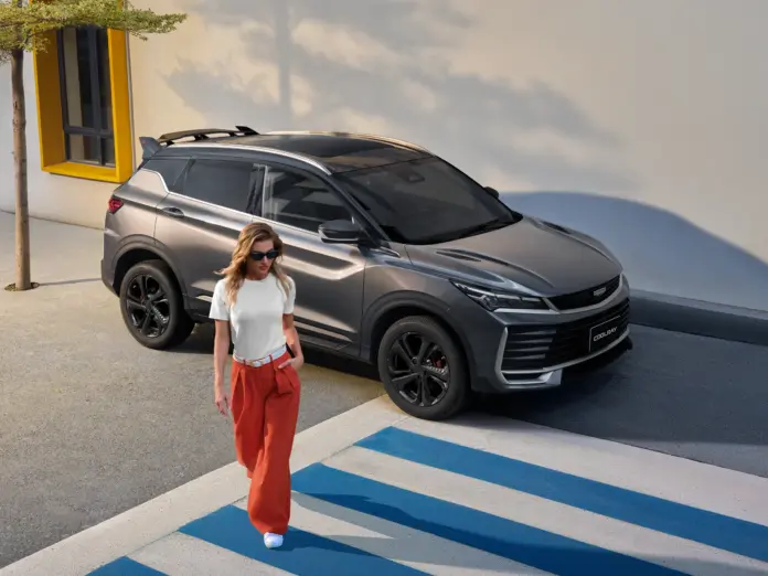 Geely Coolray gris, vista delantera lateral junto a un paso peatonal